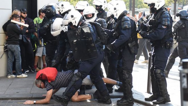 A man falls between French policemen during an anti-government demonstration called by the "yellow vest" (gilets jaunes) movement, on September 21, 2019 in Paris. - The yellow vest (gilets jaunes) protests, which often descended into violent clashes with the police, erupted last November, with demonstrators accusing French President of being aloof and unaware of the needs of ordinary French people. (Photo by Lucas BARIOULET / AFP)