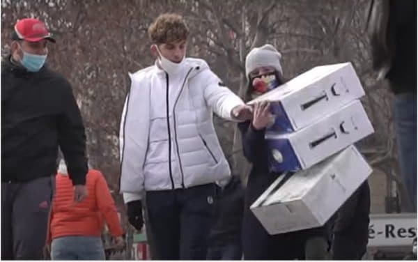 Une femme marche dans Paris avec 3 boîtes de PS5 pour piéger les passants