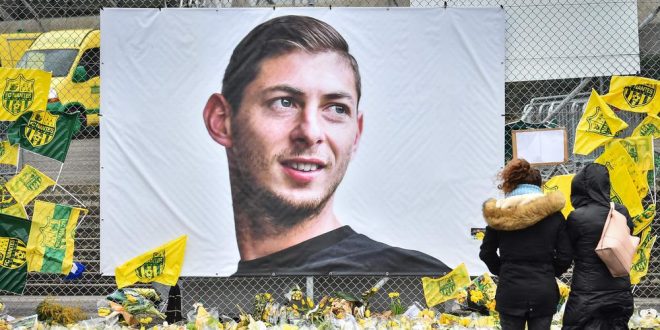 (FILES) In this file photo taken on February 8, 2019 people look at yellow flowers displayed in front of the portrait of Argentinian forward Emiliano Sala at the Beauvoir stadium in Nantes. - The chaos that has followed the tragic death of Nantes footballer Emiliano Sala on January 21, 2019 has shone an unflattering light on the murky dealings of player agents and reinforced calls to properly licence them. Even though France has stricter rules governing agents than other leading Western European football nations, at least six intermediaries have been named in connection to Sala's 17-million euro transfer from Nantes to Cardiff City in January. (Photo by LOIC VENANCE / AFP) FILES-FBL-FRA-AGENTS-BUSINESS